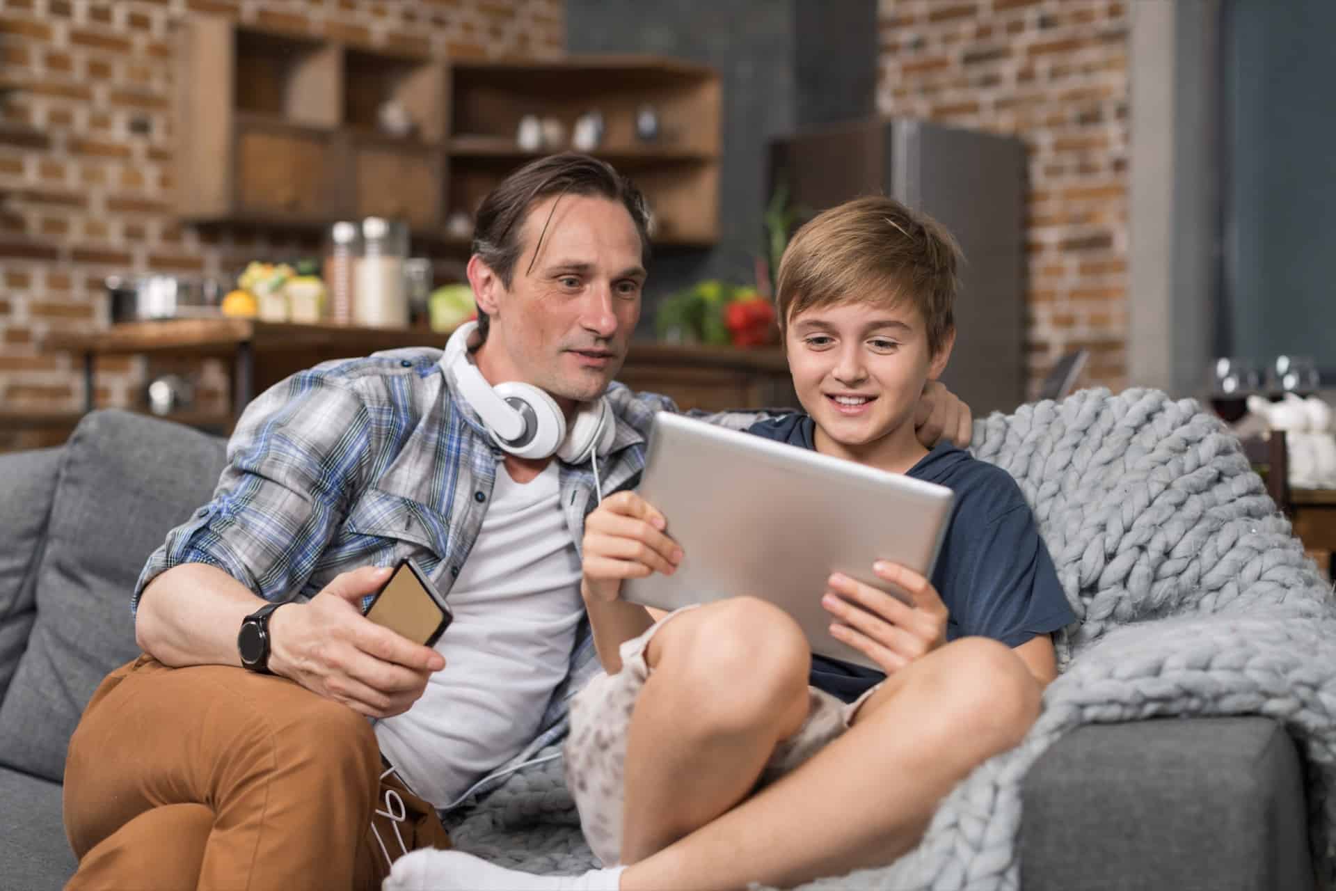 happy smiling father and son sitting on couch use FKPY7SN - 5 Things You Can Do At Home With Your Kids